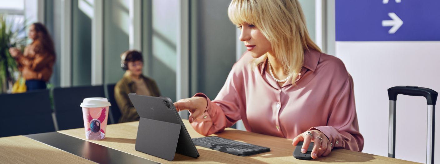 Woman working at a table with a tablet, keyboard, and mouse
