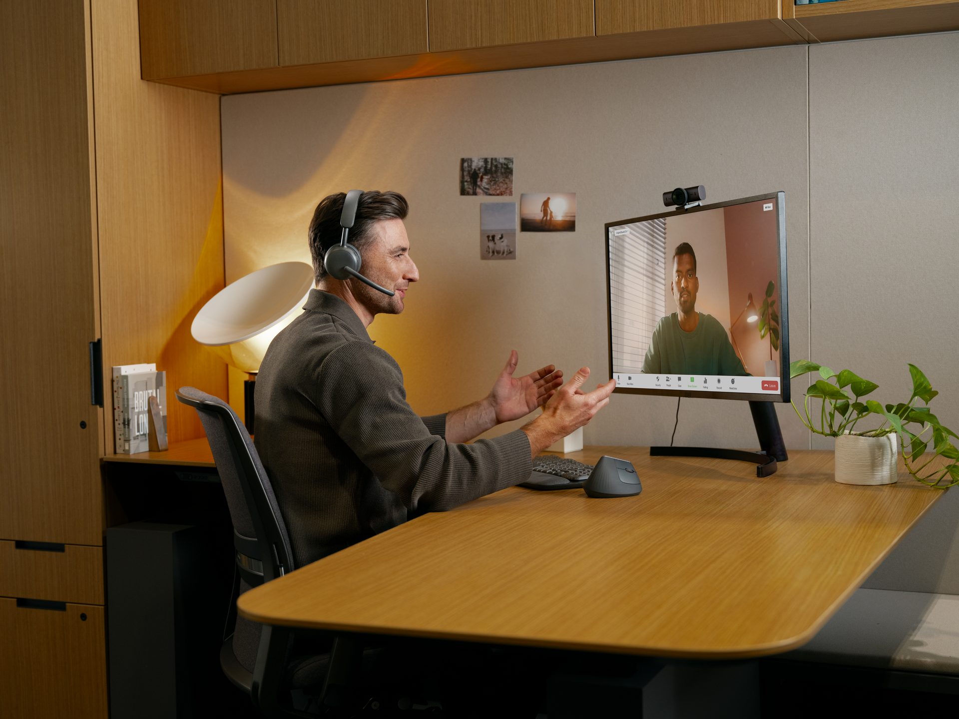 Man on a video call at a home desk wearing a headset