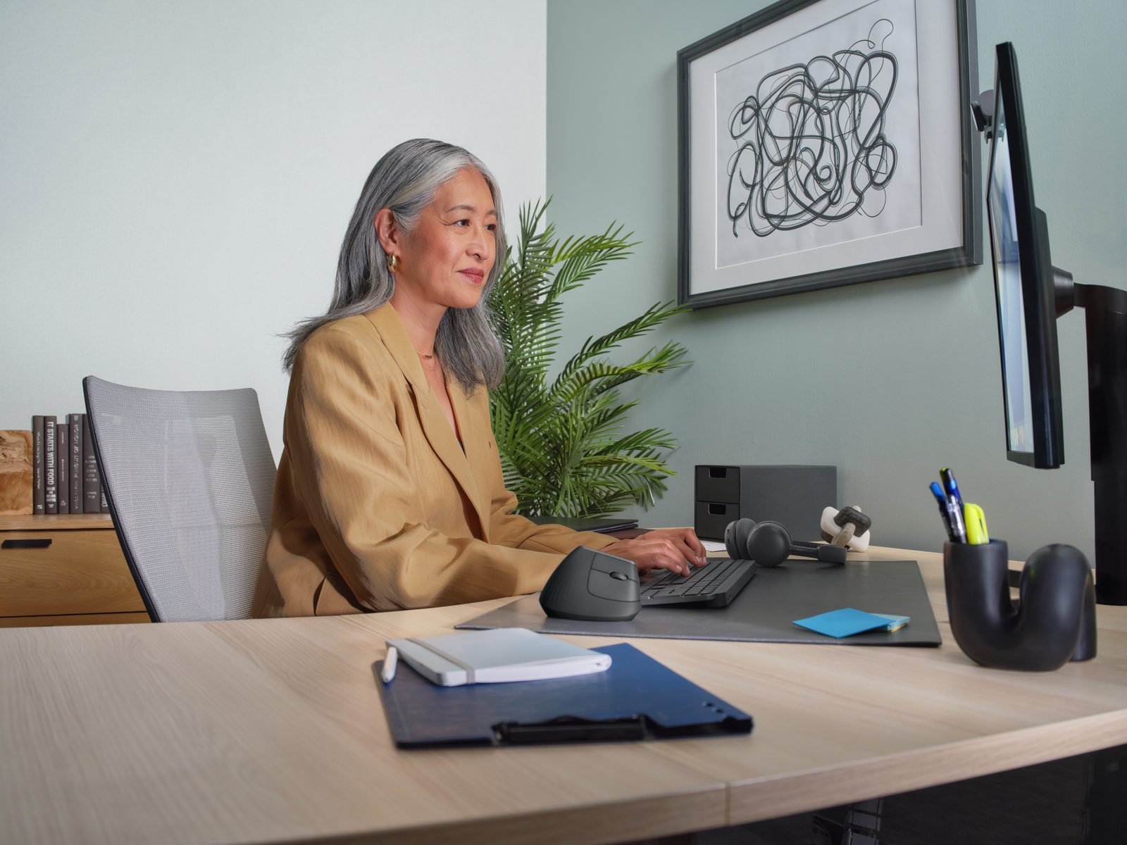 Woman working at a wooden desk with a computer and vertical mouse