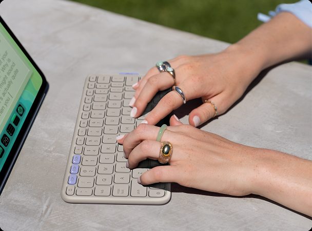 Hands using a Logitech keyboard and tablet