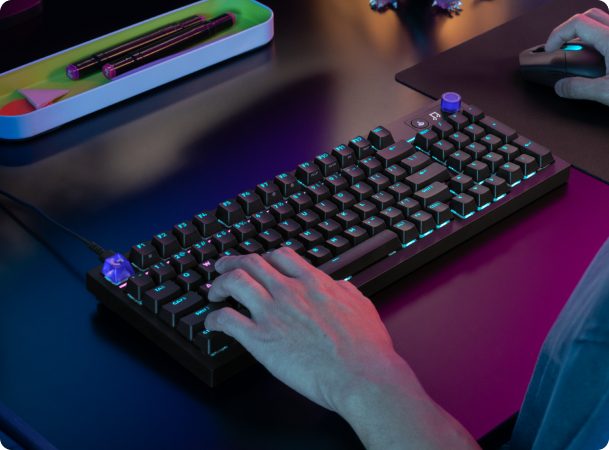 Hands typing on a backlit Logitech keyboard