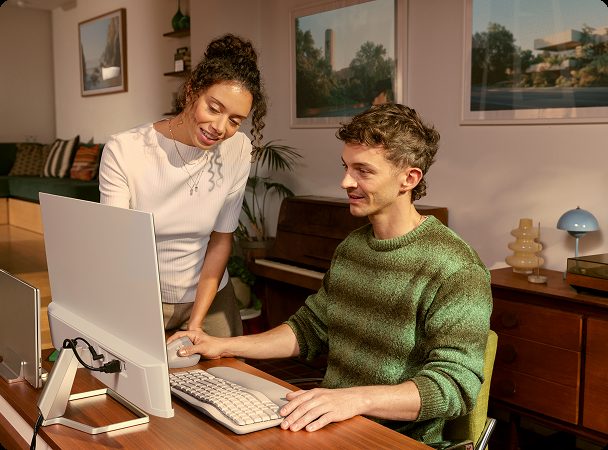 Two people looking at a computer in a home office